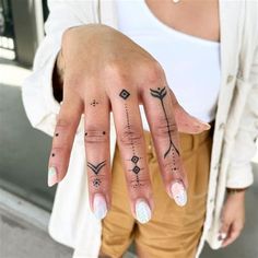 a woman's hand with tattoos on it and two fingers in front of her