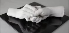 a black and white photo of two hands holding each other's hand on top of a glass surface