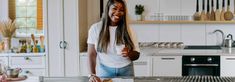 a woman standing in a kitchen next to a counter with food on top of it