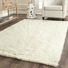 a large white rug in a living room with a chair and table next to it