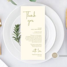 a place setting with white plates and silverware, gold cutlery and greenery