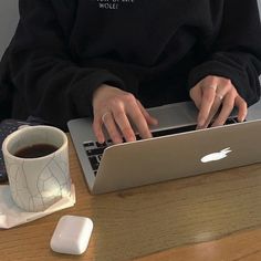 a person sitting at a table with a laptop and cup of coffee in front of them