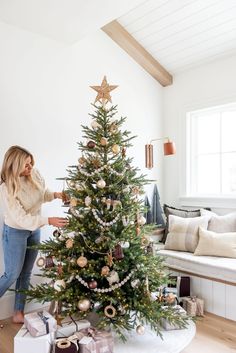 a woman decorating a christmas tree in her living room