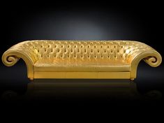 a gold colored couch sitting on top of a black floor