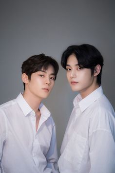 two young men standing next to each other wearing white shirts and black hair, one with his eyes closed