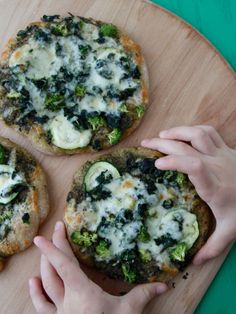 three small pizzas sitting on top of a wooden cutting board