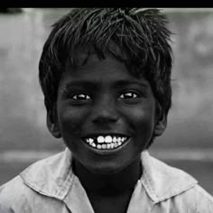 a black and white photo of a young boy with his mouth open, smiling at the camera