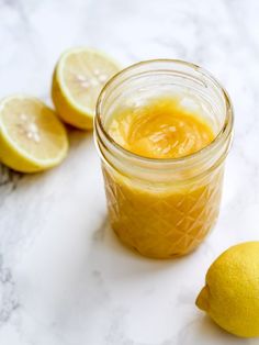 a jar filled with liquid next to sliced lemons on a white counter top,