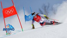 a person on skis going down a snowy hill with flags in the back ground