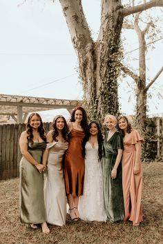 a group of women standing next to each other in front of a tree and fence