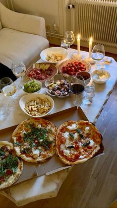 pizzas and other food on a table with candles