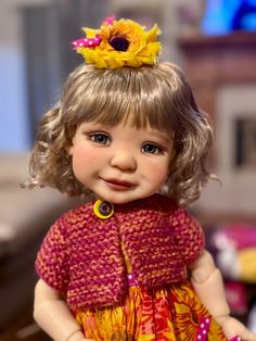 a close up of a doll wearing a dress and a flower in her hair,