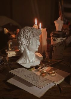 a white busturine sitting on top of a table next to candles and books