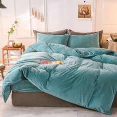 a bed with blue comforter and pillows in a room next to a lamp on a table