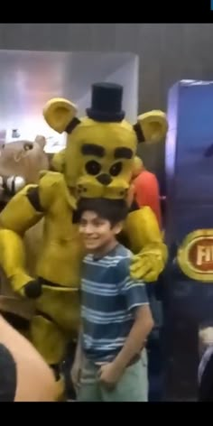 a young boy standing next to an inflatable teddy bear