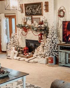 a living room decorated for christmas with stockings and trees on the fireplace mantels