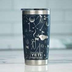 a stainless steel yeti cup with an artistic design on it's lid sits on a countertop