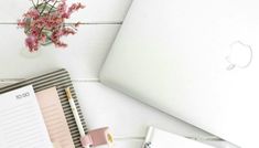 an open laptop computer sitting on top of a desk next to a notepad and pen