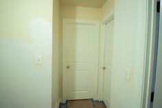 an empty hallway with two white doors and some blue tape on the floor next to it