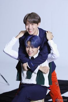 two young men are hugging each other in front of a white background and black backdrop