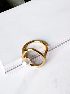 Pearl loop designed ring color: gold base: brass size: 6-6.5 Trendy Gold Pearl Ring Gift, Gold Pearl Ring With Metal Band, Metal Jewelry With Ring Detail And Modern Twist, Modern Metal Jewelry With Ring Detail, Gold Bypass Ring With Modern Twist, Trendy Gold Metal Rings, Gold Pearl Open Ring, Gold Open Pearl Ring, Minimalist Gold Pearl Ring With Detail