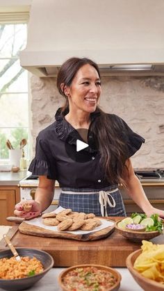 a woman standing in front of a table filled with plates and bowls full of food