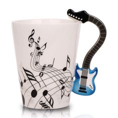 a coffee cup with a guitar handle and musical notes on the side, next to it is a ceramic mug