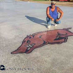 a man kneeling down in the middle of a parking lot with a drawing on it