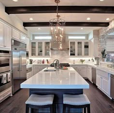 a large kitchen with white cabinets and stainless steel appliances