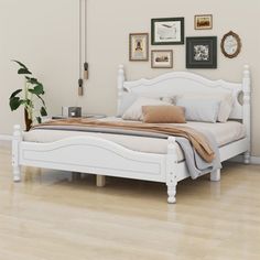 a white bed sitting on top of a hard wood floor next to a wall with pictures above it