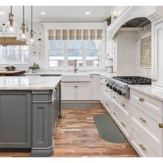 a large kitchen with white cabinets and wood flooring, along with marble counter tops