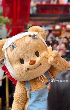 a brown teddy bear wearing overalls and a headband