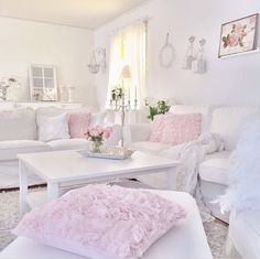 a living room filled with white furniture and pink pillows