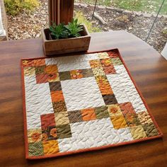 a potted plant sitting on top of a wooden table next to a patchwork quilt