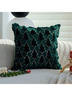 a green pillow sitting on top of a white couch next to a christmas tree decoration