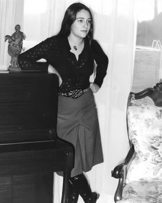 a woman standing next to a piano in a living room