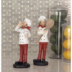 two figurines are standing next to each other near some lemons and jars