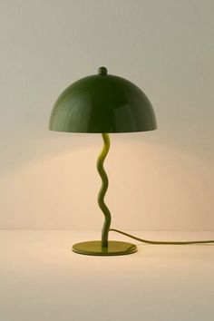 a green lamp on a white table with a light bulb in the shape of a spiral