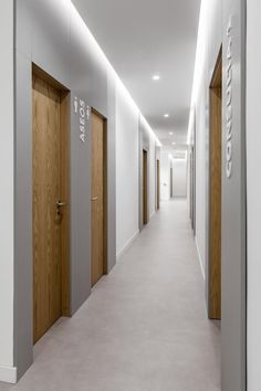 an empty hallway with wooden doors and signs on the walls, leading to another room