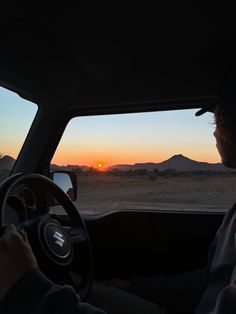 a man driving his car at sunset in the desert