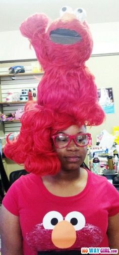 a woman with red hair and glasses is wearing a pink sesame character wig