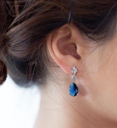 a close up of a woman's ear wearing earrings with blue stones on them