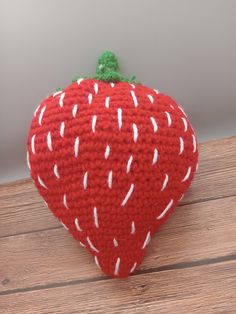 a knitted strawberry sitting on top of a wooden table