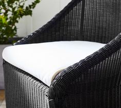 a black wicker chair with white cushions