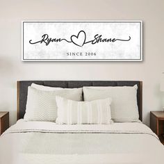 a bedroom with a bed, nightstands and a large framed sign on the wall