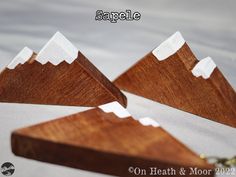 three pieces of wood with white mountain tops on each side and one piece missing from the other