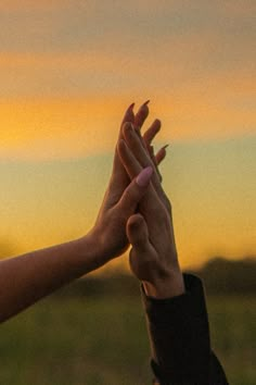 two people reaching their hands up into the air to catch something in the sky at sunset