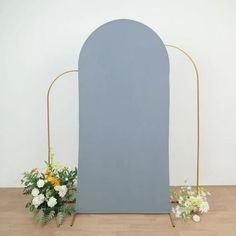 two flowers are sitting on the floor next to a blue arch with gold stand legs