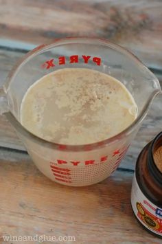 a measuring cup filled with brown liquid next to a jar of dry ingredients on top of a wooden table