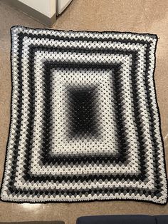 a black and white crocheted rug on the floor